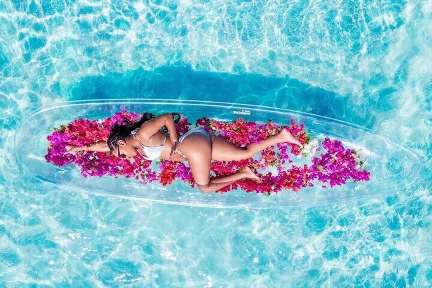 Une personne allongée sur un flotteur dans une piscine, entourée de fleurs roses. 5