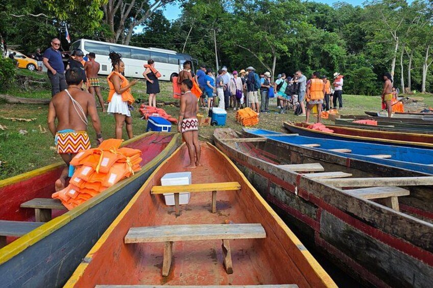 Canoes lined up on a dock with people standing around them. 3