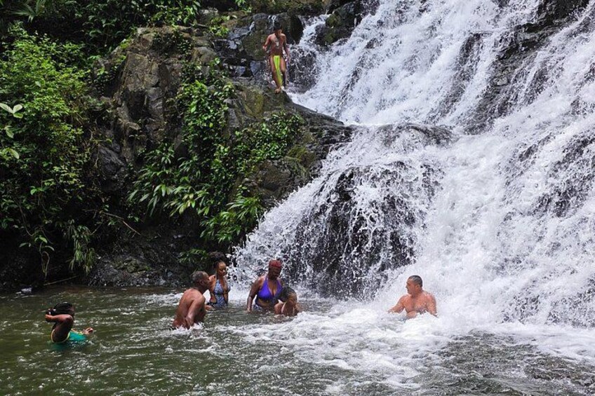 A waterfall with people swimming and enjoying the water. 2