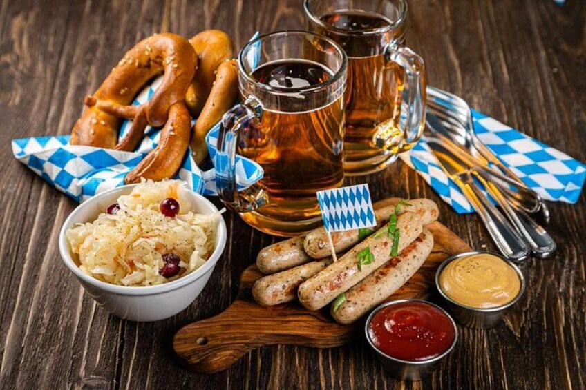 Brezel, pølser, surkål, øl og sennep på et træbord. 3
