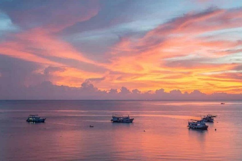 A sunset over a calm sea with boats. 1