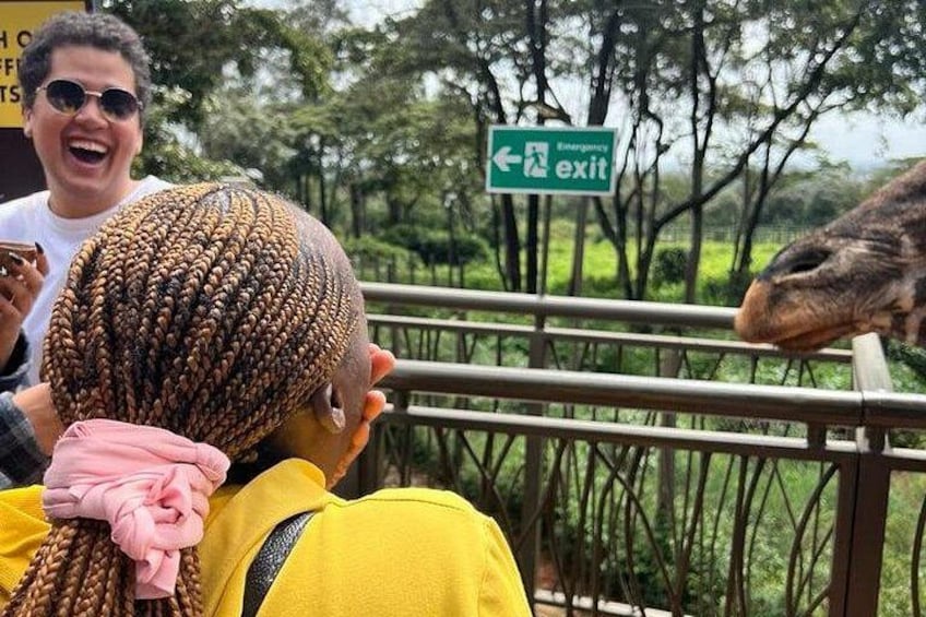 Een persoon met vlechten, een groen bord met daarop ‘uitgang’ en een giraffe. 1