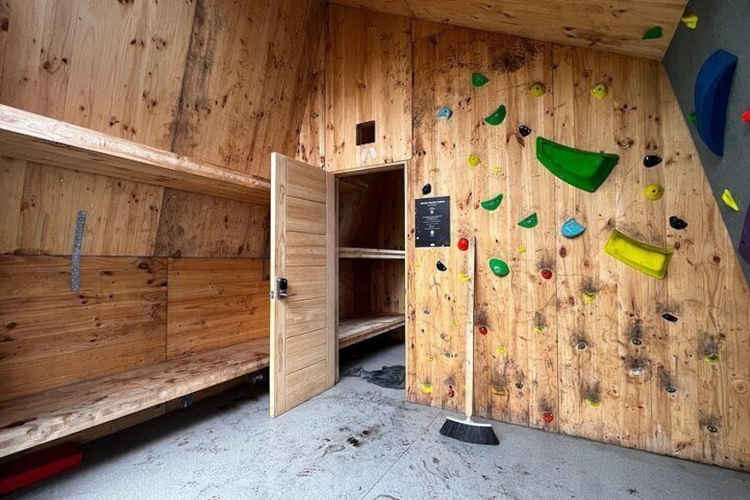 A wooden climbing wall with various holds and a door. 5