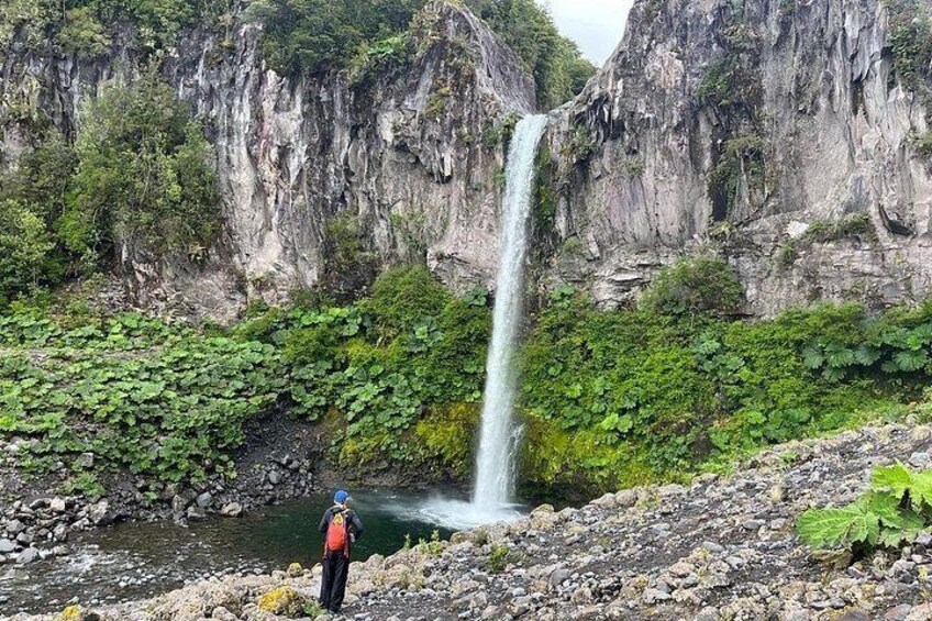 A waterfall, rocky terrain, and a person standing near the water. 2