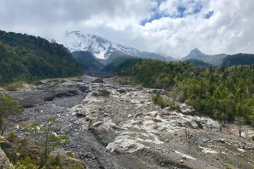 Un paisaje montañoso con un río, zonas boscosas y picos nevados. 1