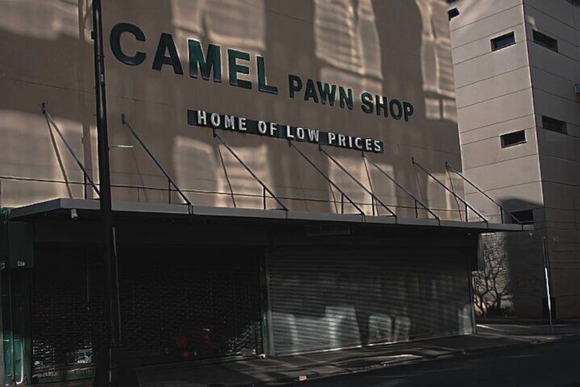 A building with a sign that reads 'CAMEL PAWN SHOP HOME OF LOW PRICES.' 2
