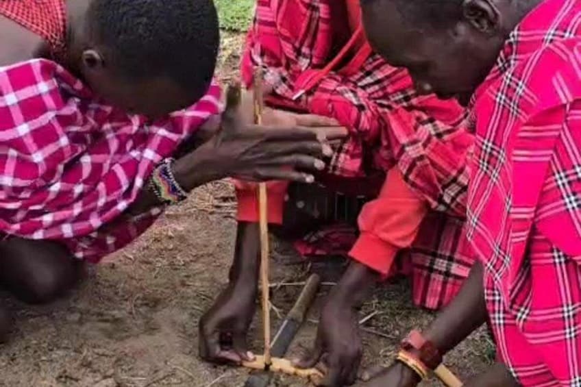 Menschen in rot-rosa Karopullover nehmen an einer Outdoor-Aktivität mit Stöcken und einer kleinen Konstruktion teil. 5