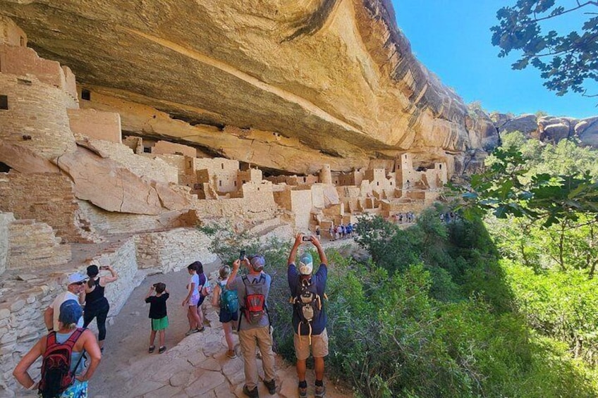 A group of hikers on a rocky trail with ancient cliff dwellings. 2