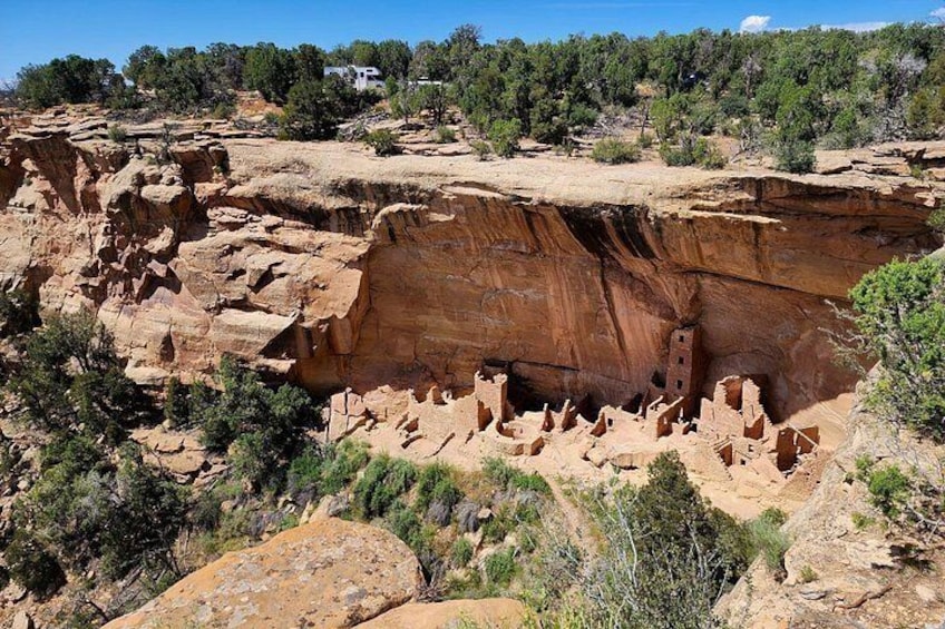 A canyon with red rock formations, a small building, and sparse vegetation. 5