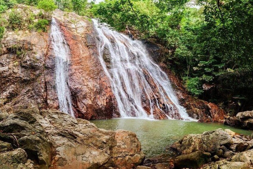 Una cascada se precipita sobre un risco rocoso hacia un estanque rodeado de abundante vegetación. 2