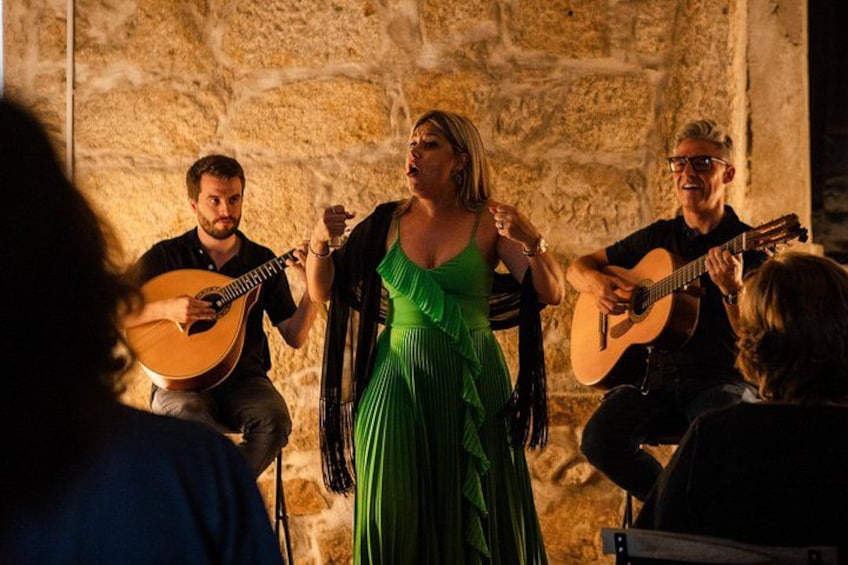 A group of people playing guitars and singing in a stone-walled room. 3