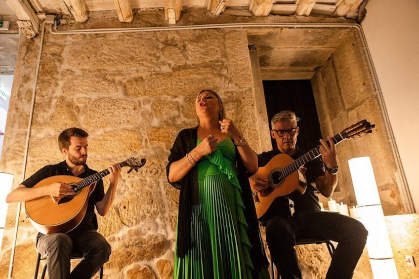 Three people playing guitars in a stone building. 4