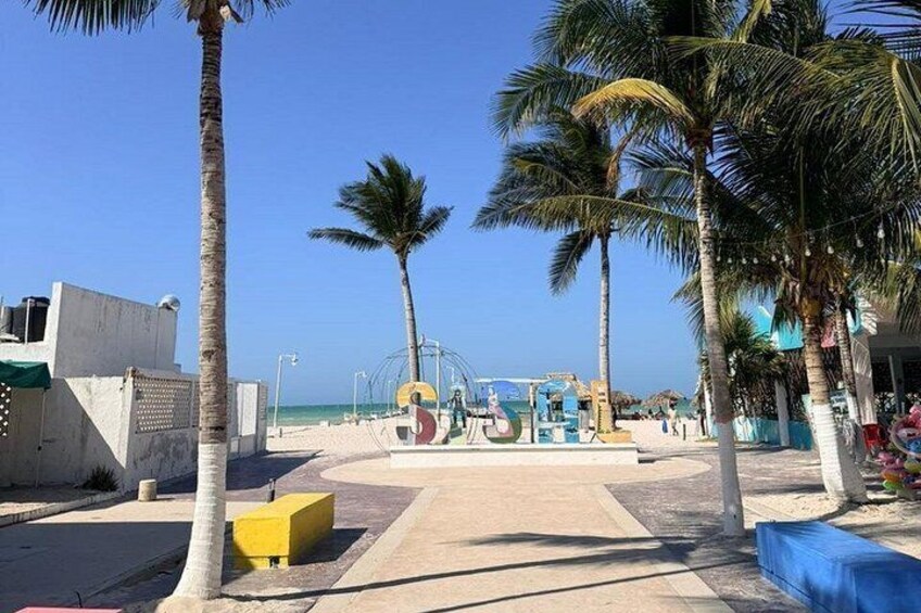 A beach with palm trees, a playground, and a clear blue sky. 2