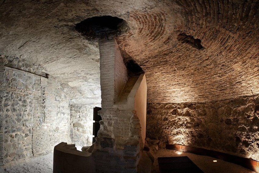 Une structure ancienne en pierre, dotée d’un grand pilier central, de murs bruts et d’une voûte. 1