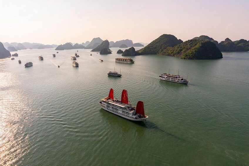 A cruise ship with red sails navigating through a body of water surrounded by green islands. 4
