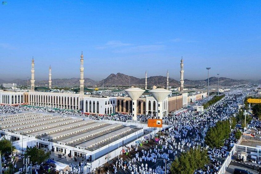 A large mosque with multiple minarets and a crowd of people. 1