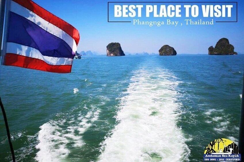 A boat in Phangnga Bay, Thailand, with a Thai flag and a clear view of the sea and rock formations. 3