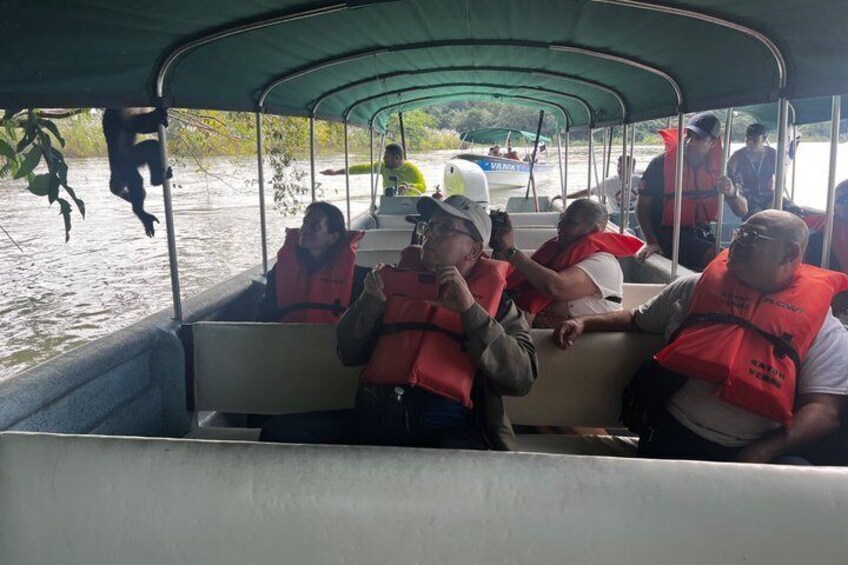 People on a boat wearing life jackets, with a river and another boat in the background. 3