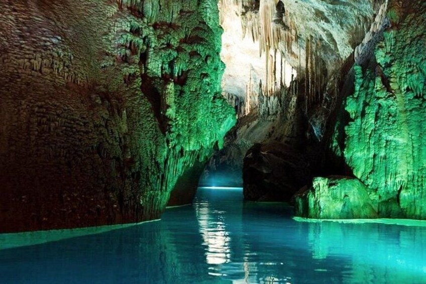 A cave with stalactites and stalagmites, a pool of water, and a narrow passageway. 1