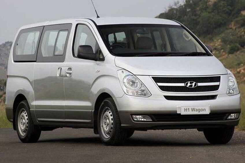 A silver H1 Wagon parked on a road with a hilly landscape in the background. 4