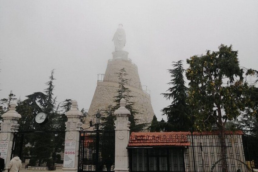 A monument with a statue on top, surrounded by trees and a clock. 5