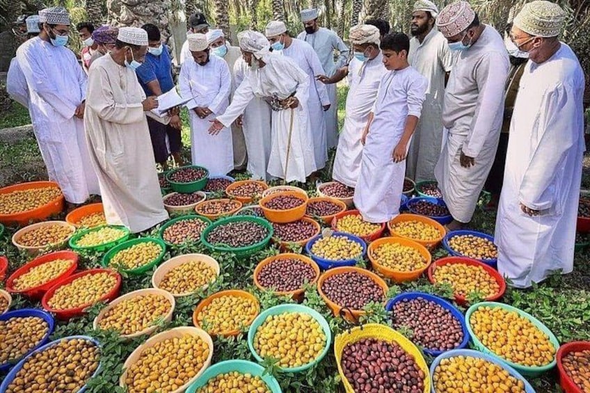 Un gruppo di uomini in abiti tradizionali in piedi attorno a ciotole colorate di noci e frutta secca. 1