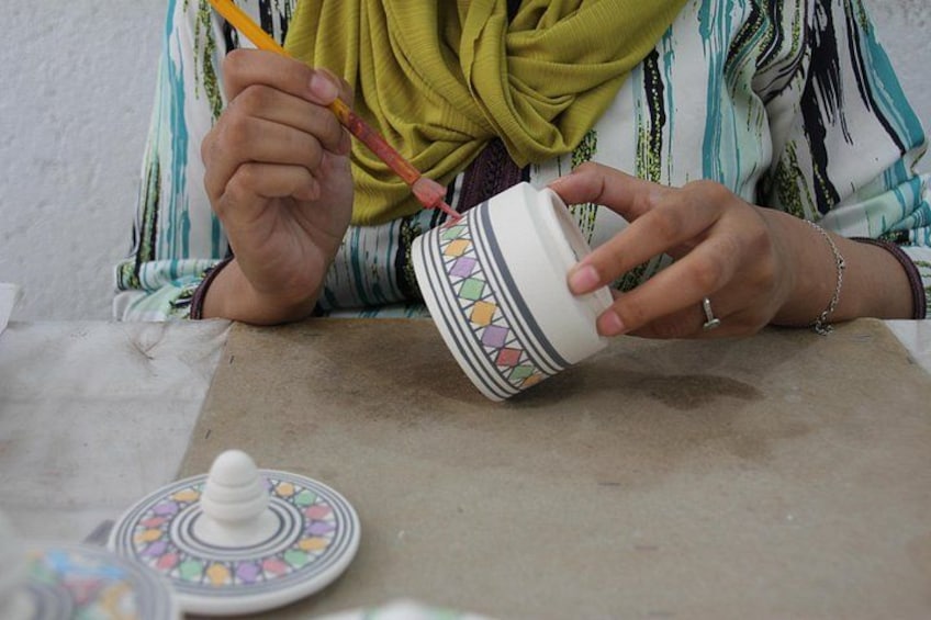 Una persona pintando una maceta de cerámica. 1