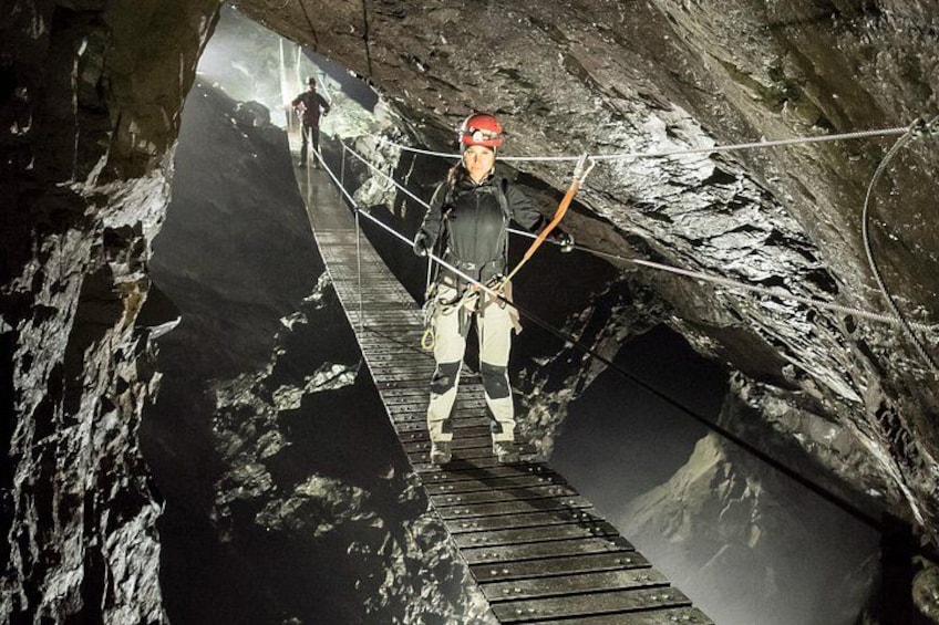 A person rappelling down a rocky, narrow path with ropes and harnesses. 1