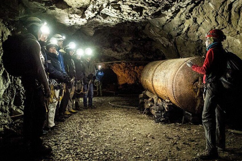 A group of people in a cave with a large cylindrical object. 4