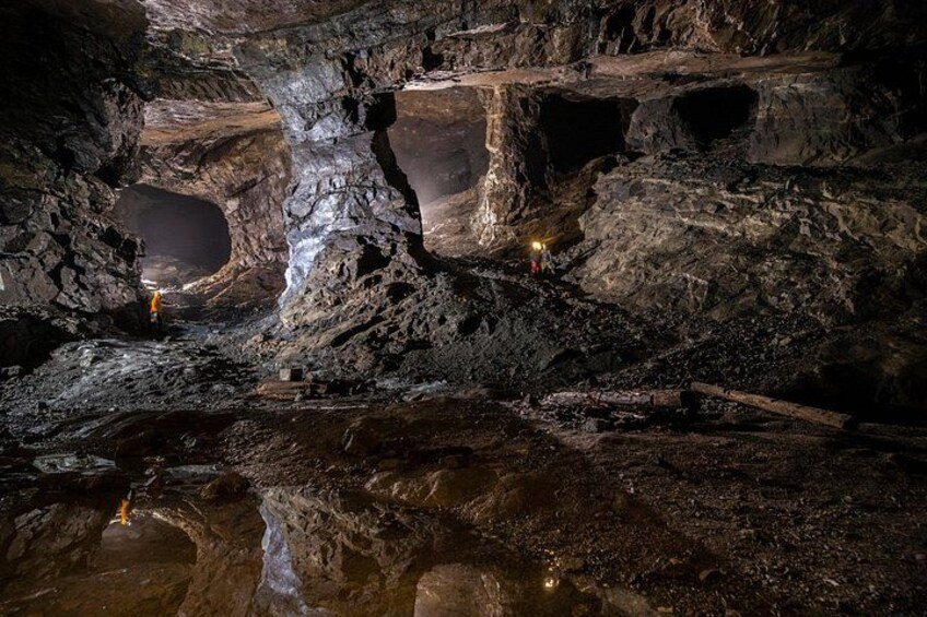 A cave with large rock formations and a person holding a light source. 2