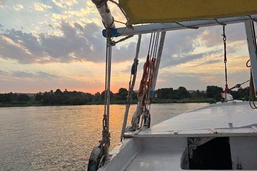 Un bote con cubierta blanca, cuerdas y un toldo. Al fondo, un río, árboles y un cielo al atardecer. 2