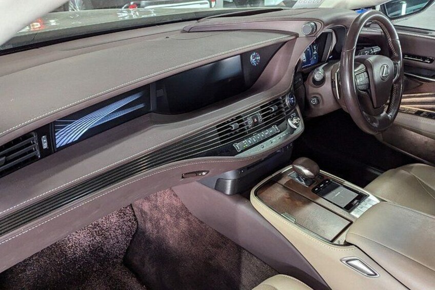 Interior de un automóvil de lujo con volante de cuero, consola central con palanca de cambios y pantalla digital. 2