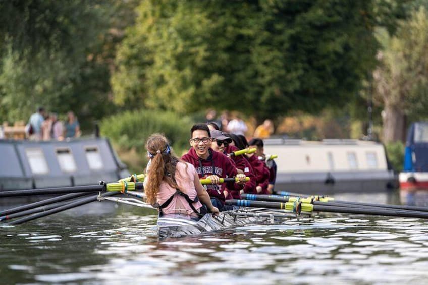 En gruppe mennesker ror i en båd på stille vand. 4