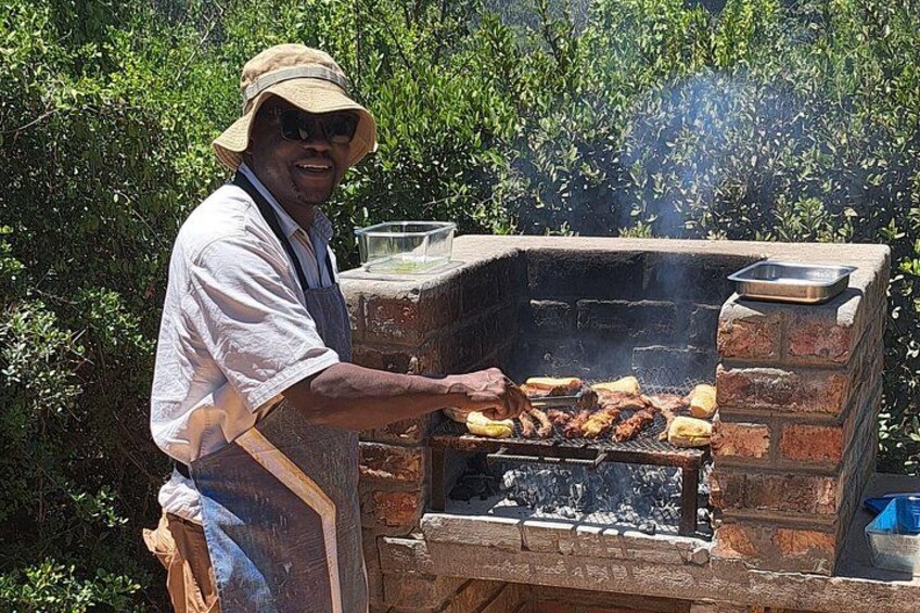 A person grilling food outdoors with a brick grill and a pot on top. 4