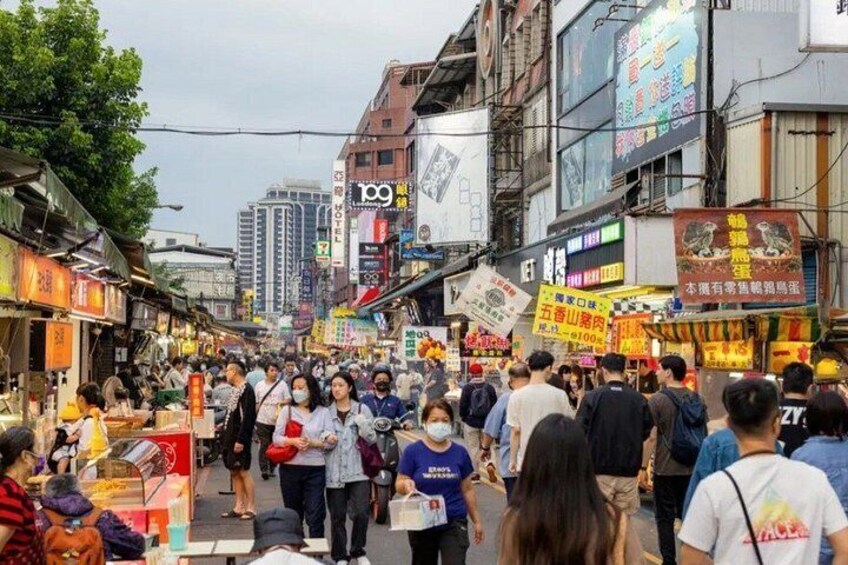 A crowded street with people walking, shops, and buildings. 3