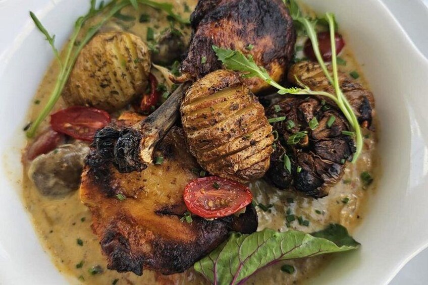 A dish with grilled meat, mushrooms, and cherry tomatoes in a creamy sauce. 5