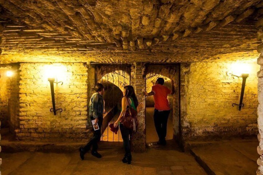 A stone-walled corridor with two people walking and one person entering a doorway. 3