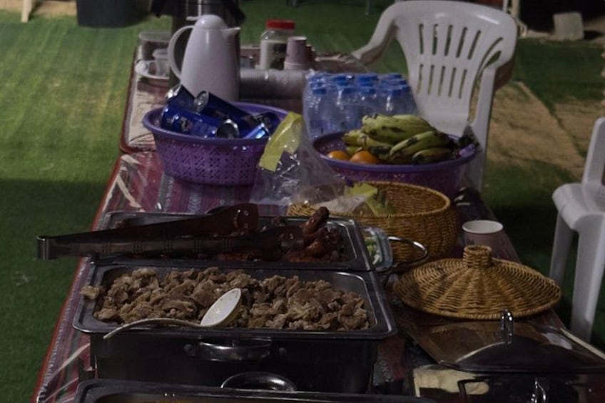 Una mesa de buffet con diferentes alimentos, una cafetera y sillas de plástico. 2