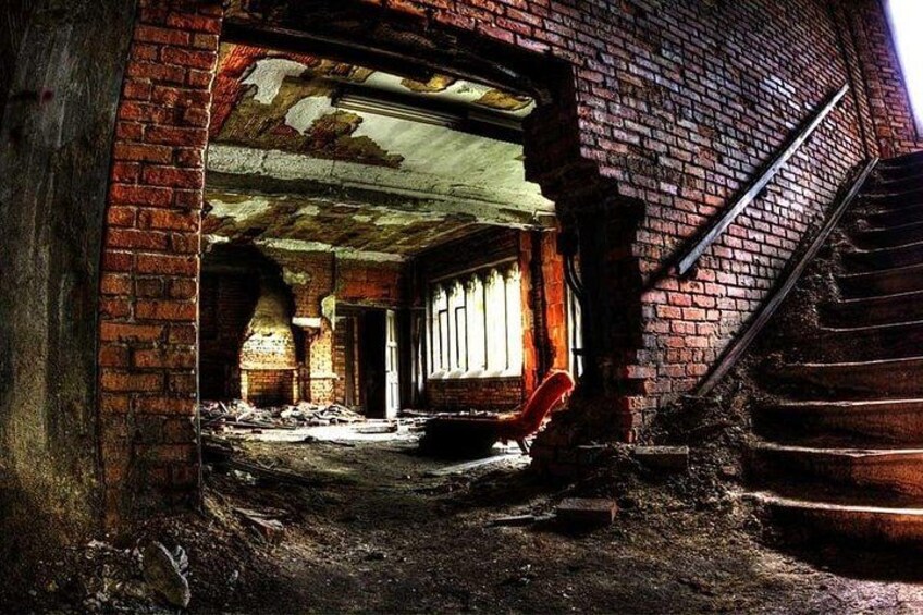 Un edificio ruinoso con paredes de ladrillo visto, un techo derrumbado y una escalera que conduce al piso superior. 3