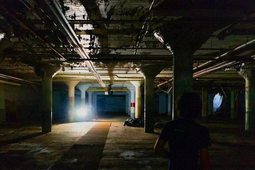 Un edificio abandonado, tenuemente iluminado, con una persona de pie al frente. 2