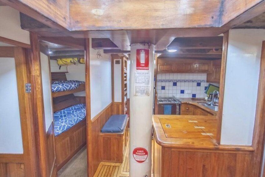 A narrow corridor with bunk beds, a wooden counter, and a kitchen area with a tiled backsplash. 4