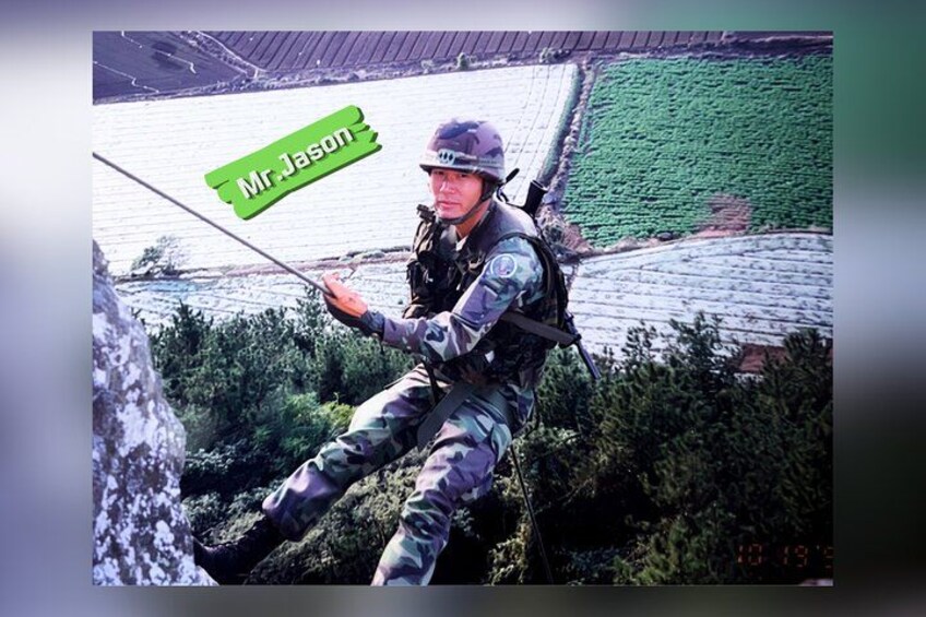 A person in military camouflage attire rappelling down a rocky surface. 3