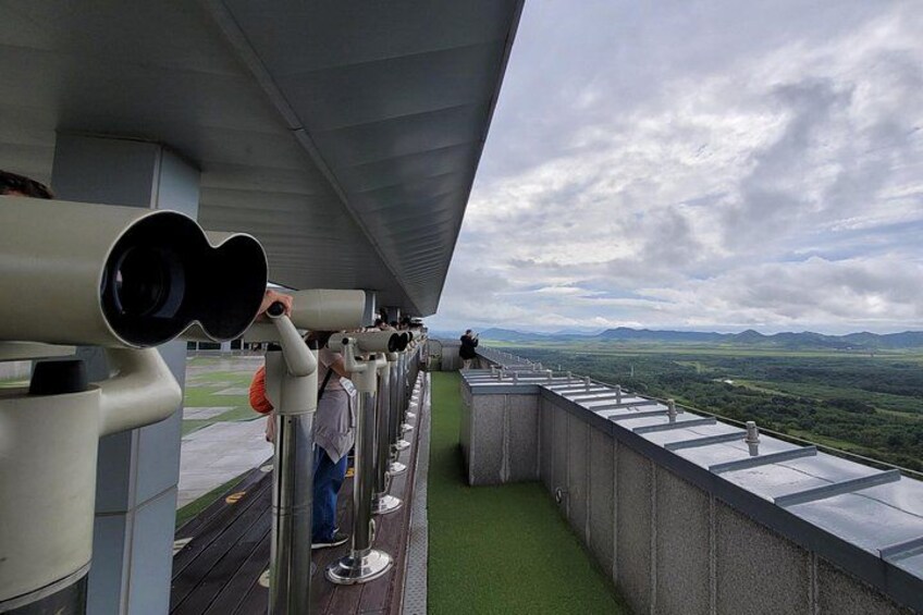 Eine Aussichtsplattform mit Teleskopen, die über eine Landschaft blickt. 4