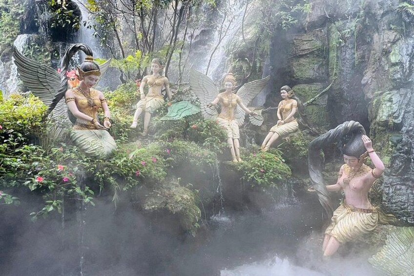Statues of winged figures in a lush, misty forest setting. 2