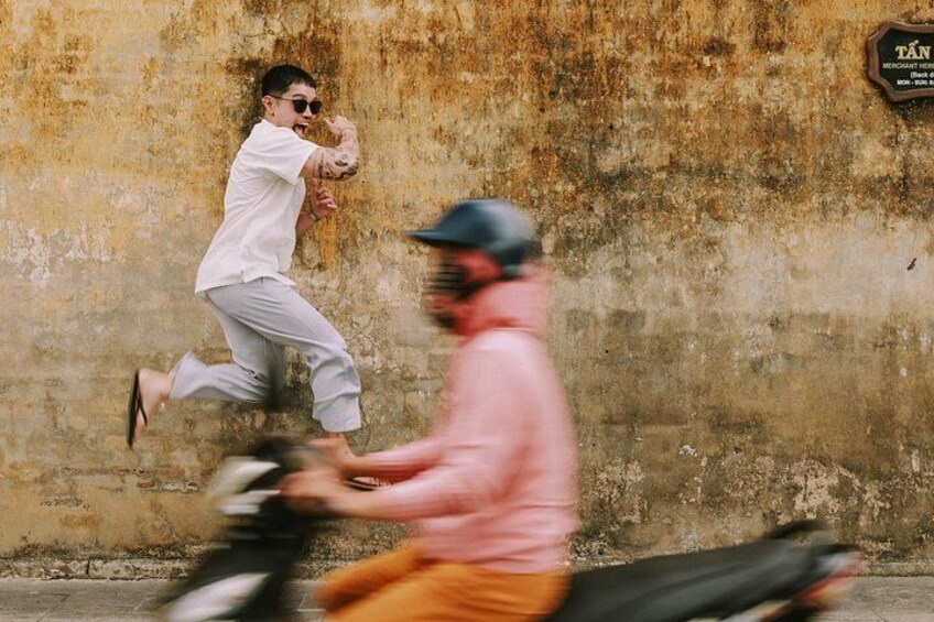 A person running and a motorbike in motion against a textured wall. 1