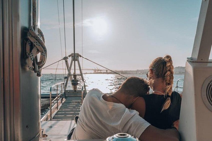 A couple embracing on a boat with a view of the sea and a bridge in the background. 5