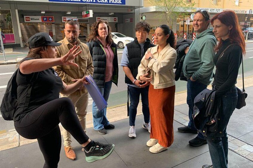 A group of people standing on a sidewalk, engaged in a discussion. 1