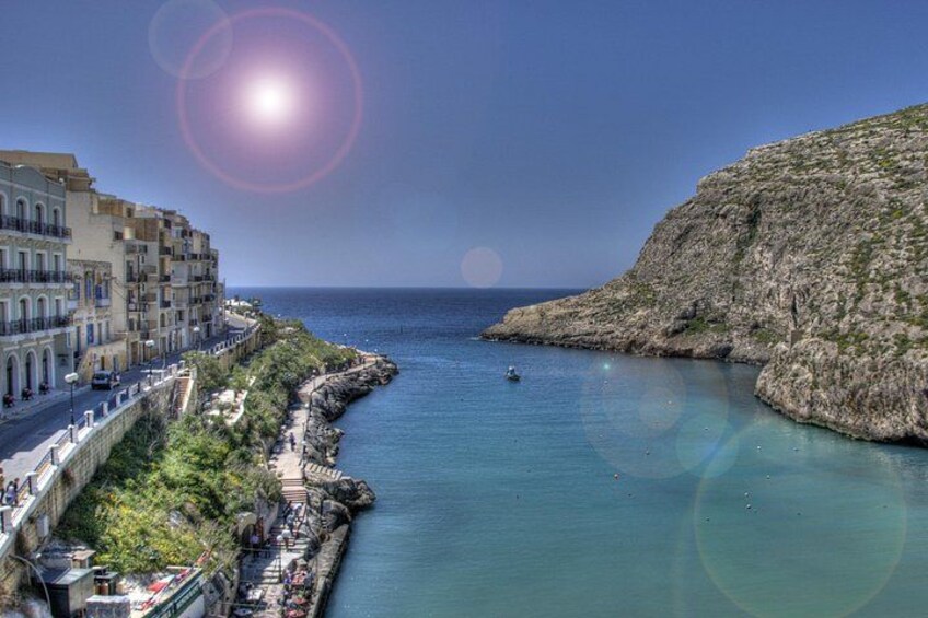 A coastal town with buildings along the waterfront, a clear sky, and calm sea. 4