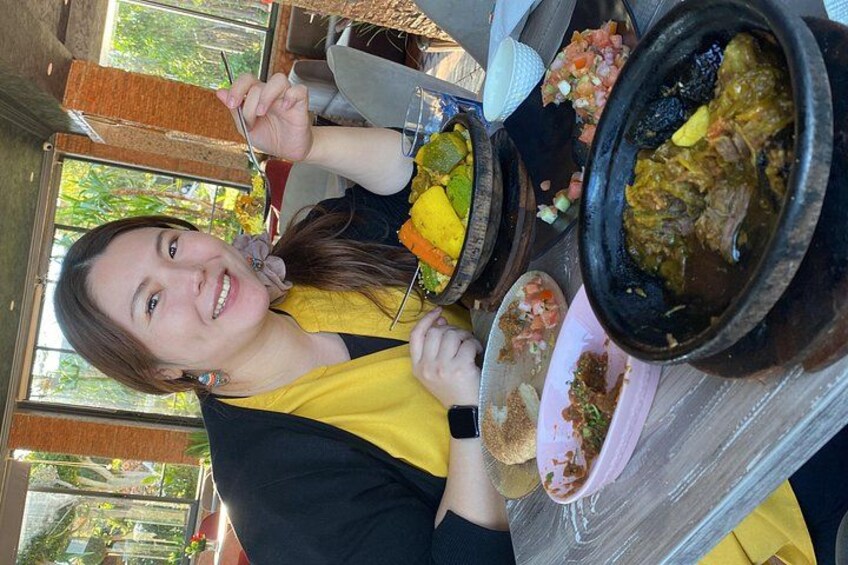 A person sitting at a table with various dishes, including a bowl of stew and a plate with a yellow item. 2