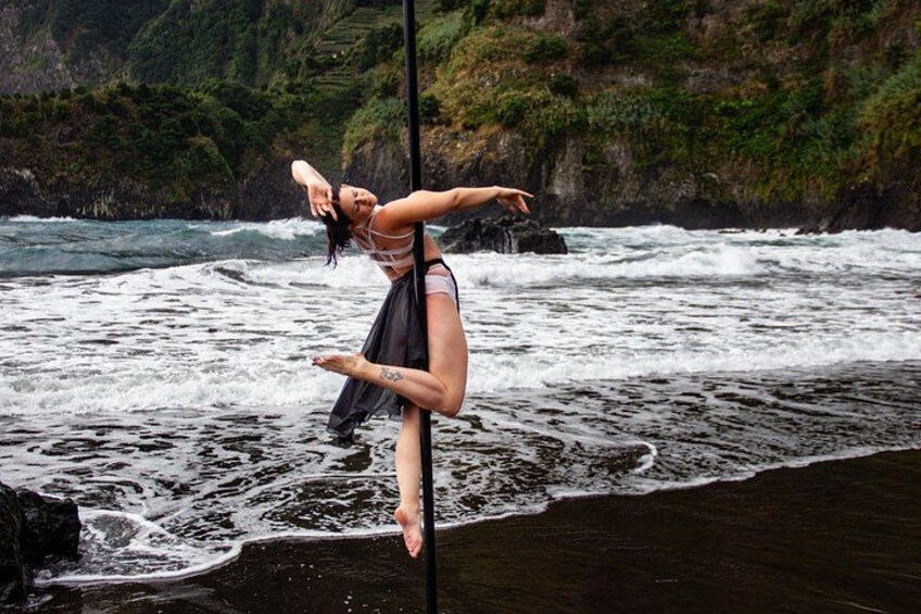 A person performing a dance on a pole by the ocean. 2